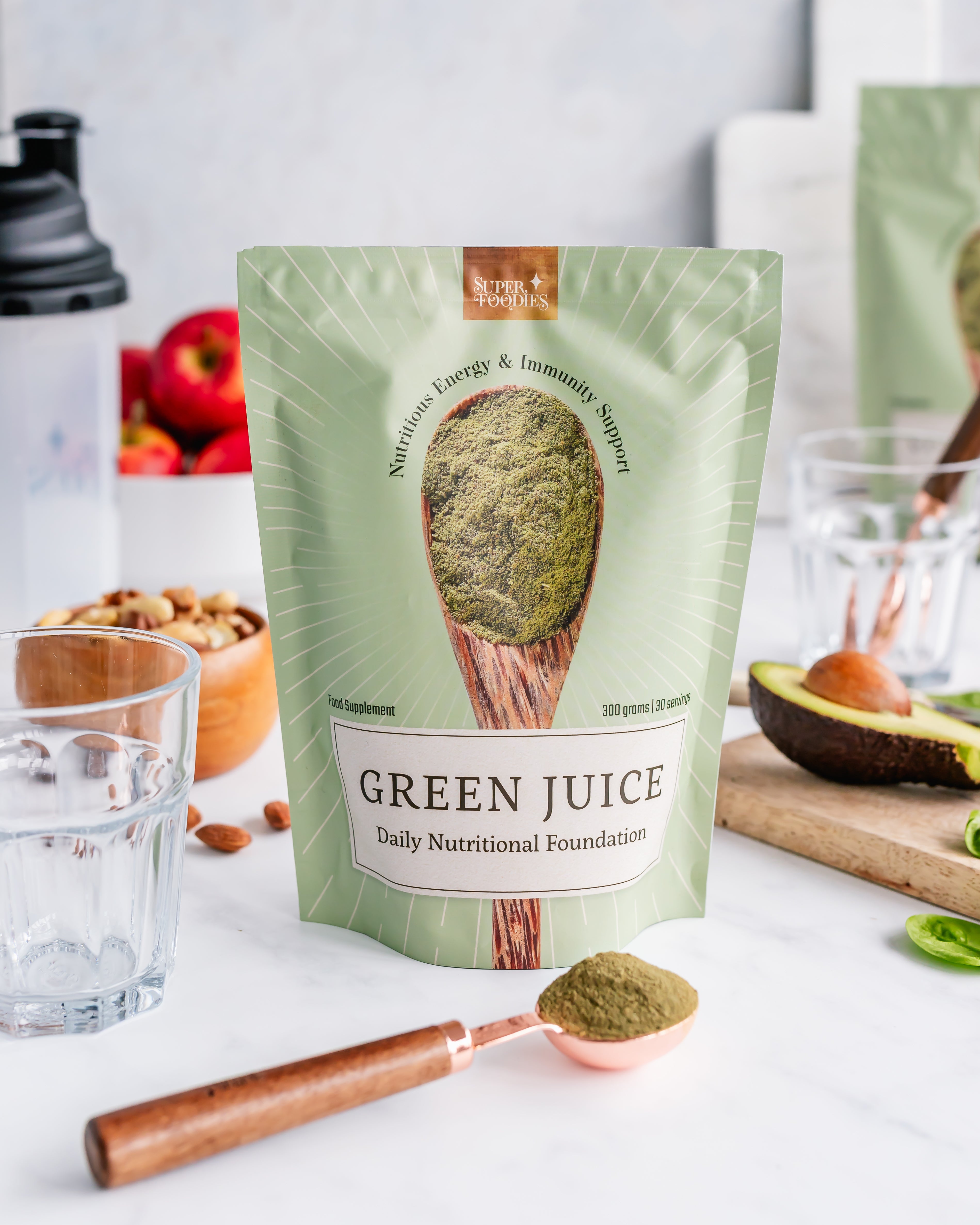 Superfoodies Green Juice pouch op marmeren werkblad met copper scoop en groen poeder